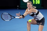 A tennis player lunges to play a backhand return in the Australian Open at Melbourne Park.