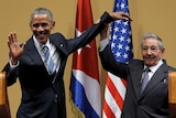 Raul Castro holds Barack Obama's hand in the air after a press conference.
