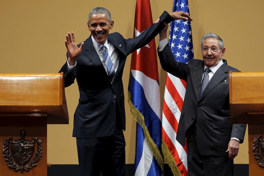 Raul Castro holds Barack Obama's hand in the air after a press conference.