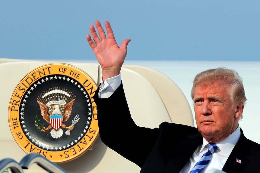 US President Donald Trump waves as he arrives at Joint Base Andrews.