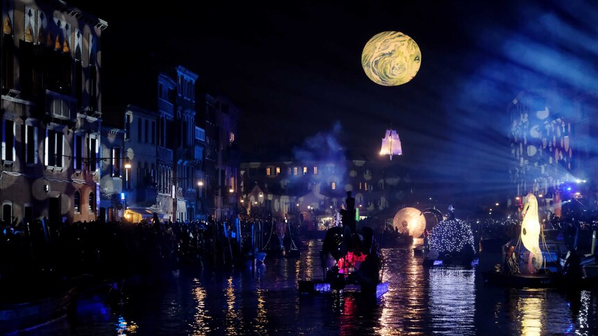 People crowd a Venice canal to watch a light show.
