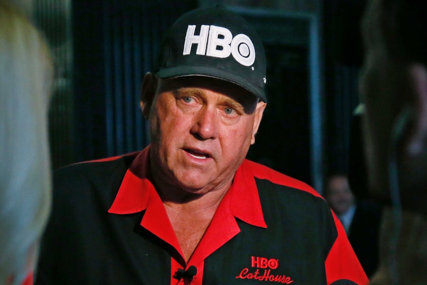 A man wearing a large black and red shirt and cap