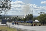 Smoke rises out of the ground in a cordoned-off area of bushland.