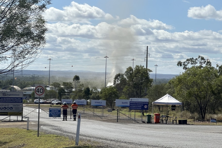 Smoke rises out of the ground in a cordoned-off area of bushland.