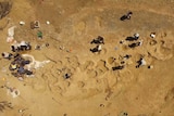 An aerial view of dinosaur tracks with people working around them.