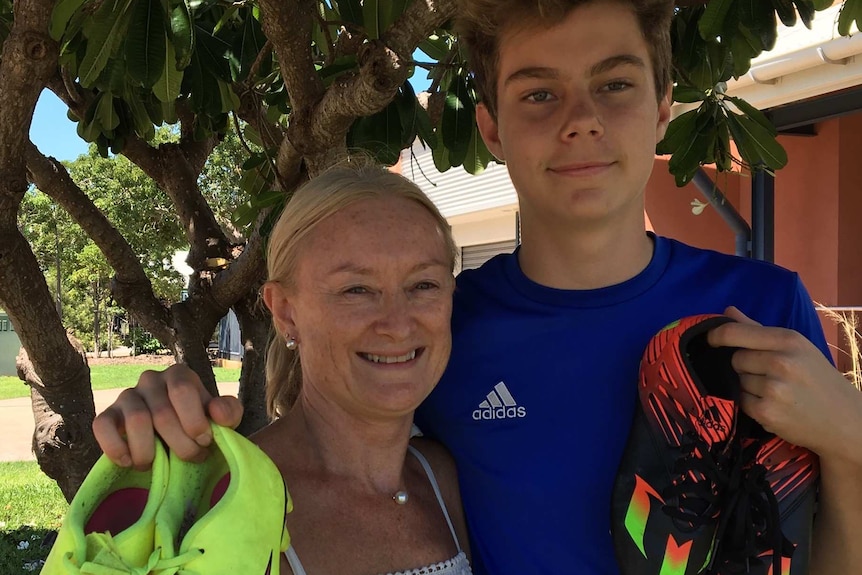 Mother, Rachel with son, Max holding two pairs of football boots