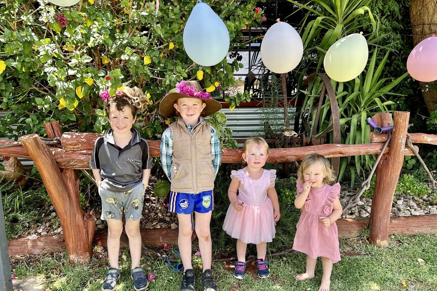 Four children smile in a garden