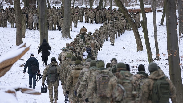 Hundreds of people in military uniform march in the snow