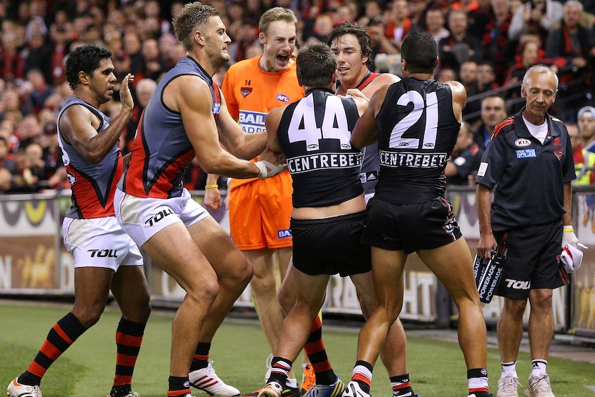 A melee breaks out as Stephen Milne and Ahmed Saad (R) wrestle with Essendon's Michael Hibberd.