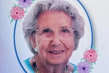 A picture of a smiling woman with grey hair and glasses inset in a circle with flowers on it