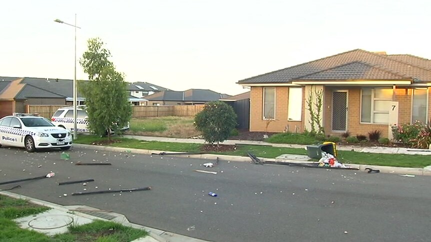 Rocks, rubbish and damaged property are strewn across the street outside a home.