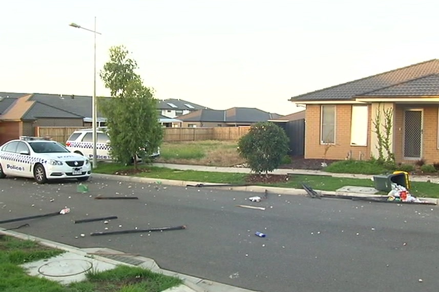 Rocks, rubbish and damaged property are strewn across the street outside a home.