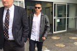 Adam David Peters walks outside Fremantle Magistrates Court with sunglasses on behind another man.