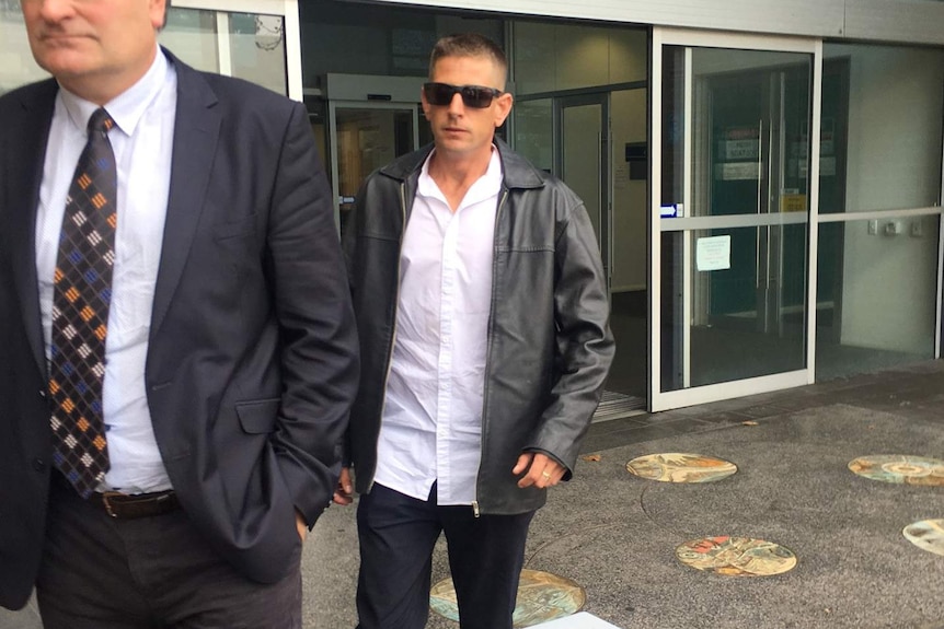 Adam David Peters walks outside Fremantle Magistrates Court with sunglasses on behind another man.