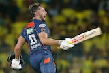 Batter Marcus Stoinis shouts as he runs, carrying his bat and helmet in his hands during an IPL game.