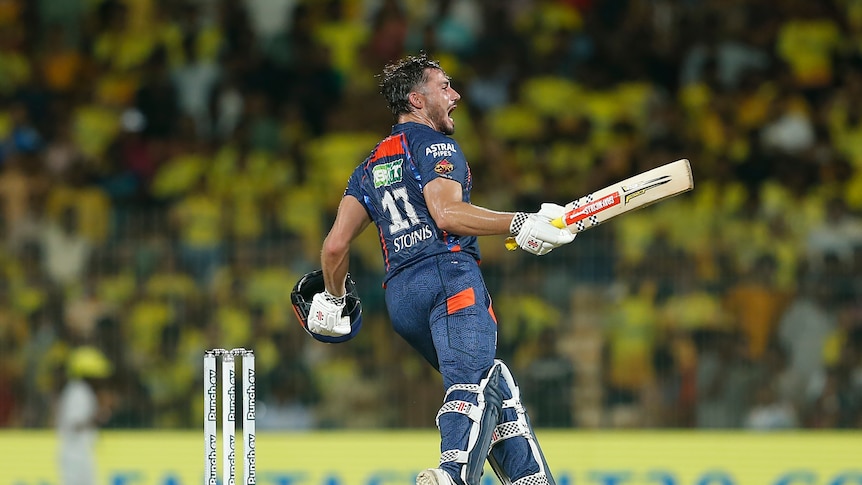 Batter Marcus Stoinis shouts as he runs, carrying his bat and helmet in his hands during an IPL game.