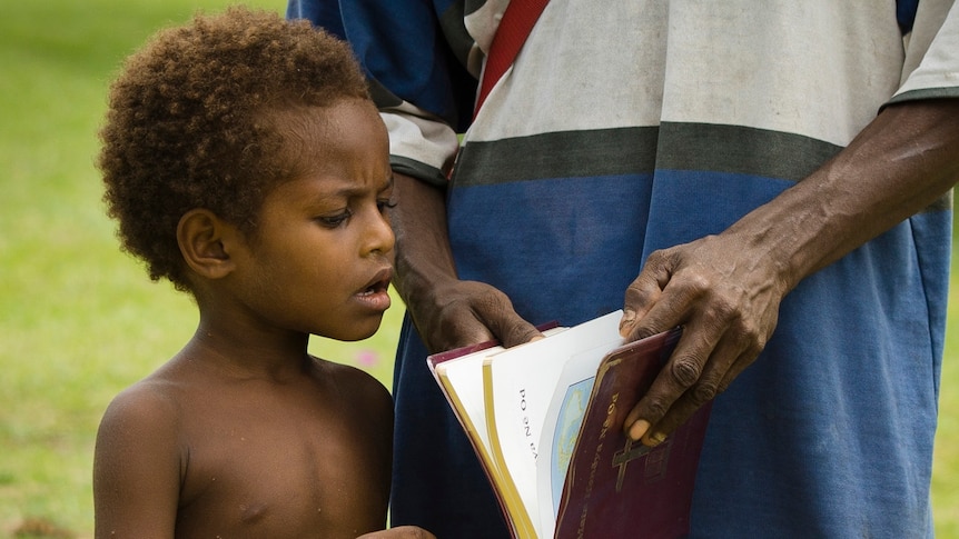 A child in Madang province reads the Bible with his father