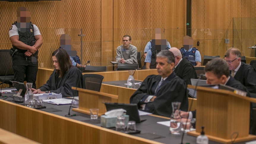 Brenton Tarrant sitting behind a glass enclosure in a court room