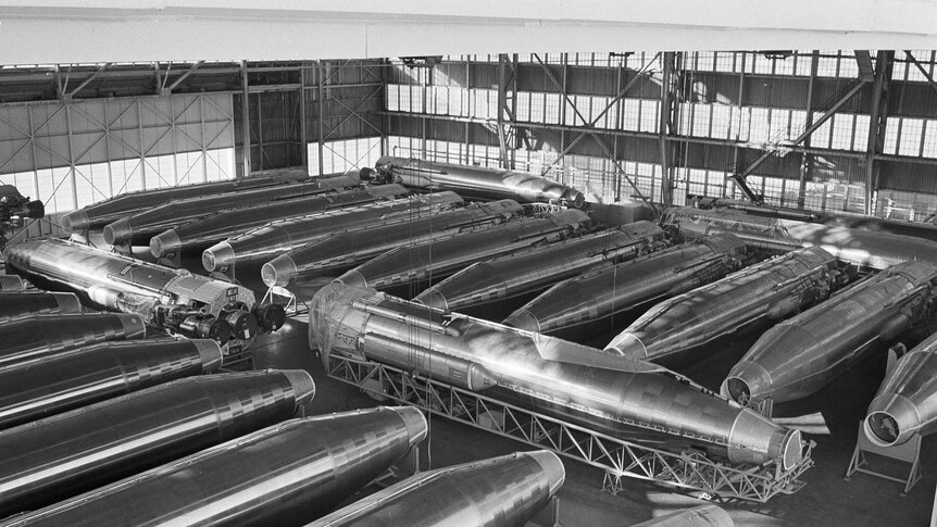 Black and white photo of a warehouse full of old fashioned nuclear missiles