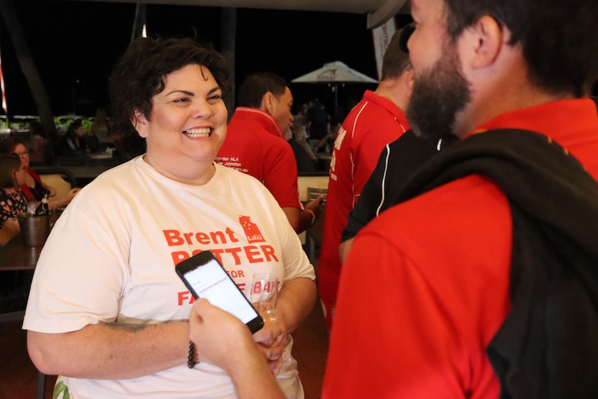 A woman wearing a shirt that says 'Brent Potter' smiles at a man opposite her. 