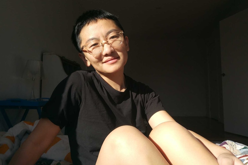 Jinghua Qian smiles as she sits posing for a photo with light shining on her face.