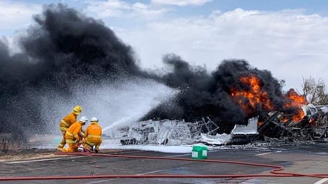 Three fire fighters spraying water on fire and smoke