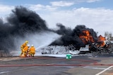 Three fire fighters spraying water on fire and smoke