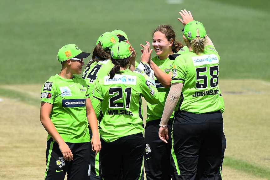 Hannah Darlington and the Thunder gather and smile as they celebrate a wicket.