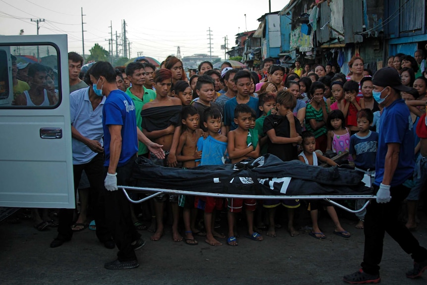 Children along Road 10 in Navotas, north of Manila, watch as mortuary workers retrieve the body of Raymond Sarmieto.