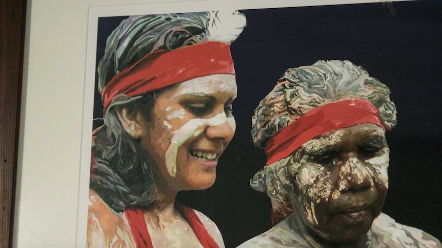 An Aboriginal artwork on a wall depicts two Indigenous dancers wearing face and body paint.