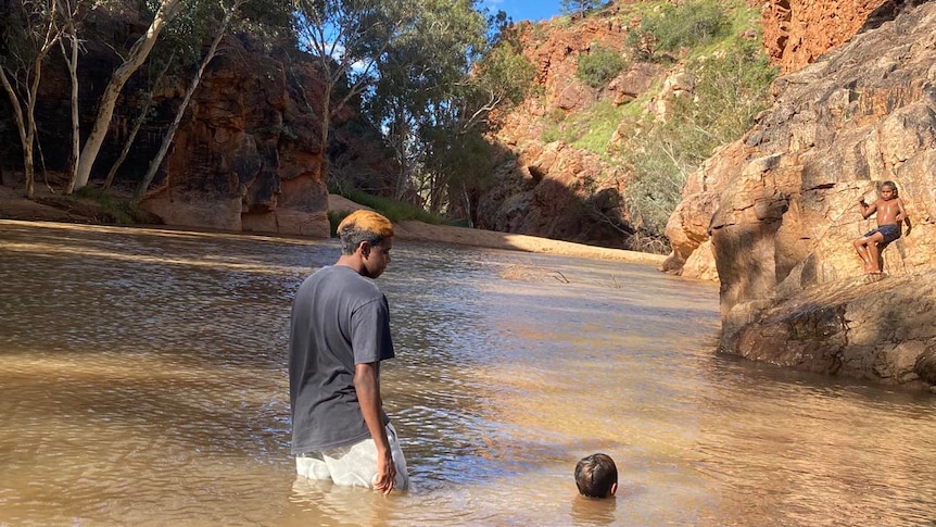 Two boys swim in a waterhole in an Aboriginal community near Alice Springs 
