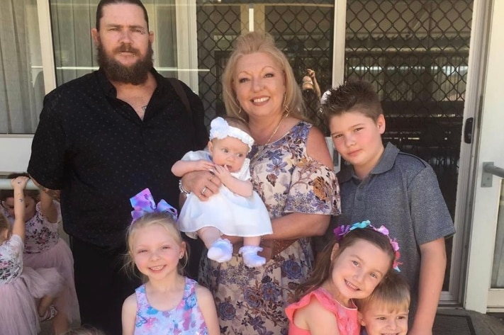 A grandmother poses for a family photo with her son and grandchildren