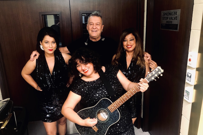 Elly-May and three family members stand together, one holds a guitar.