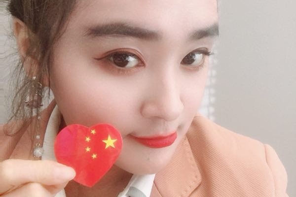 A Chinese woman taking a selfie, while one hand holds a sticker of China's national flag