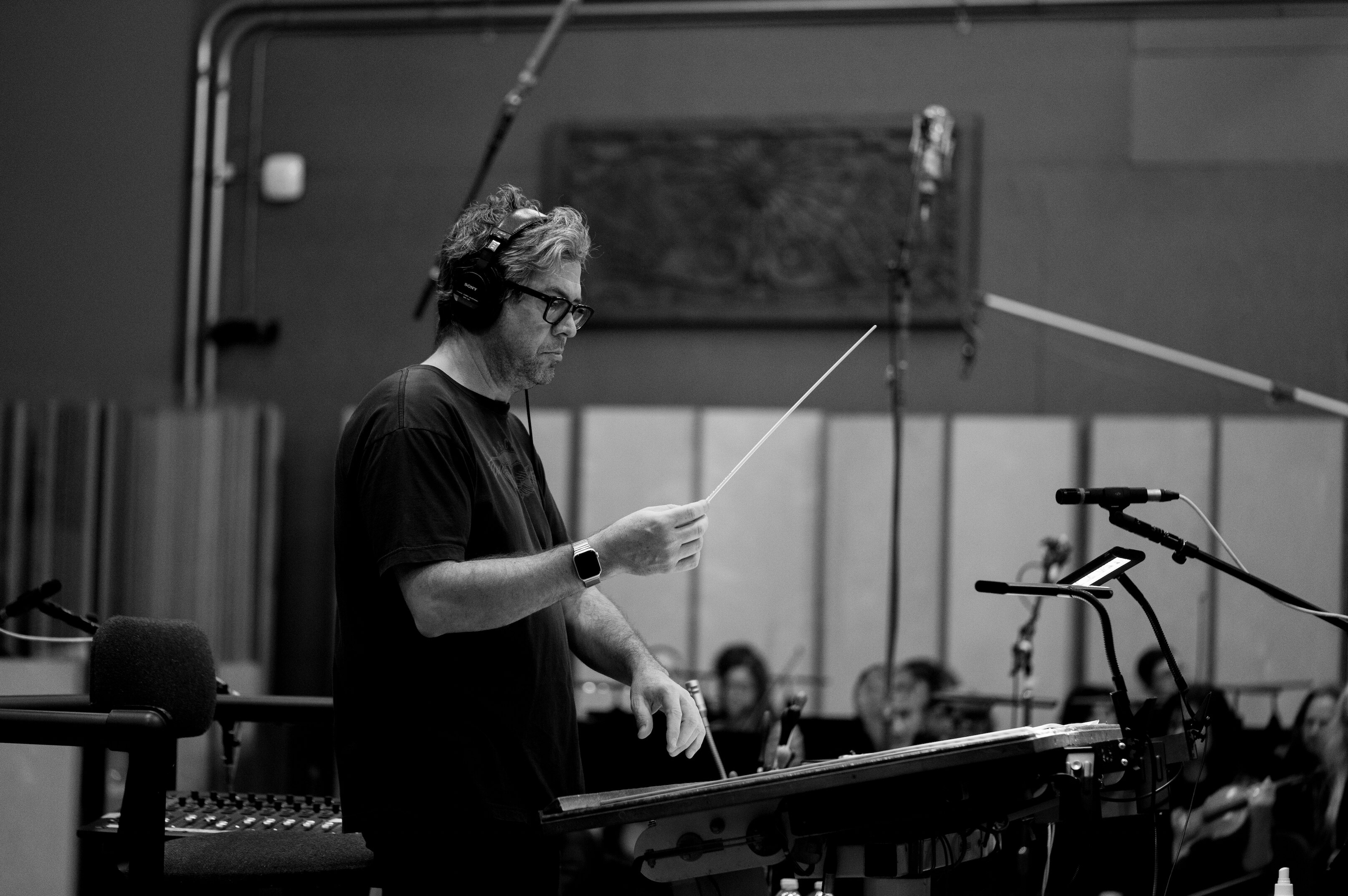 A black and white photo of a man conducting in a studio.