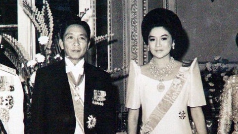 A black and white photo of Imelda and Ferdinand Marcos dressed in finery and adorned with jewels.