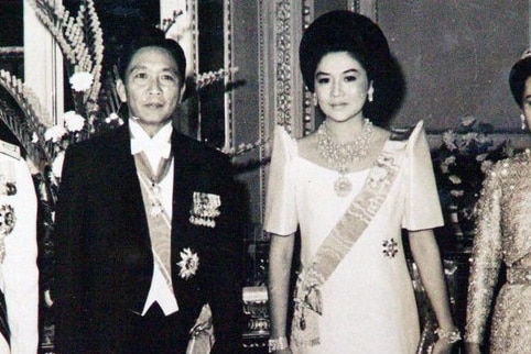 A black and white photo of Imelda and Ferdinand Marcos dressed in finery and adorned with jewels.