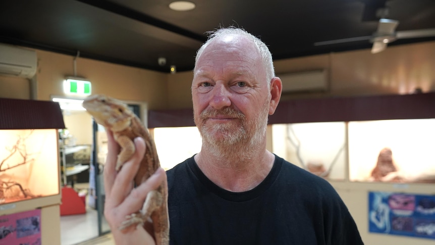 Man holds up Lizard in reptile shop