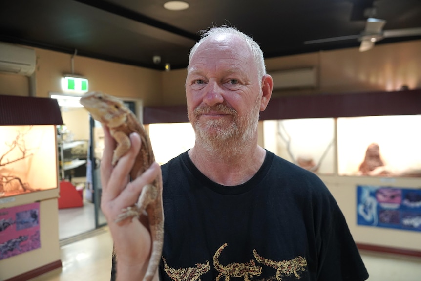 Hombre sostiene un lagarto en una tienda de reptiles