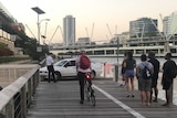 Police and security guards attempt to remove a car from a boardwalk along the Brisbane River.