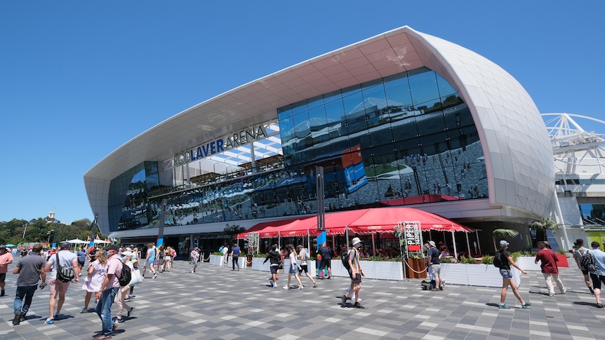 People walk around a square, modern-looking structure with glass and Rod Laver Arena written on it.