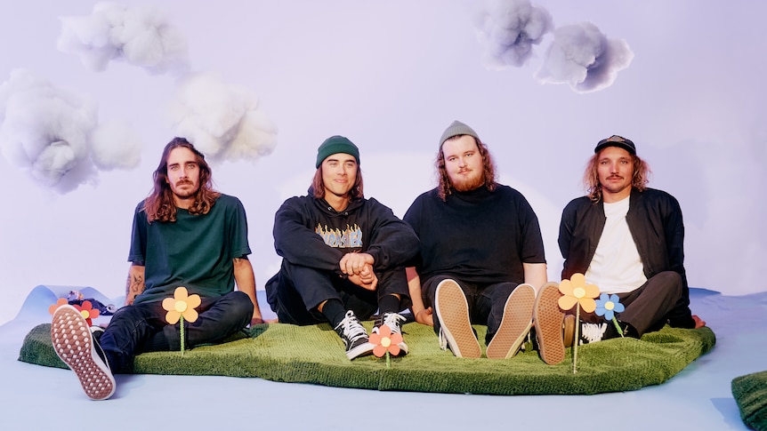 WA band Sly Withers sitting on a fake lawn with clouds painted in the background