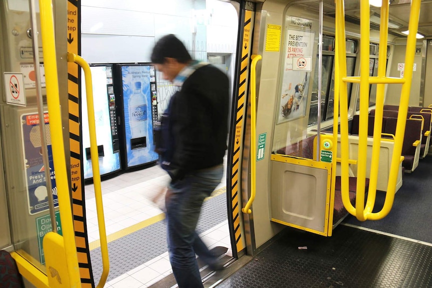 Blurred image of a man moving to exit a Brisbane train carriage