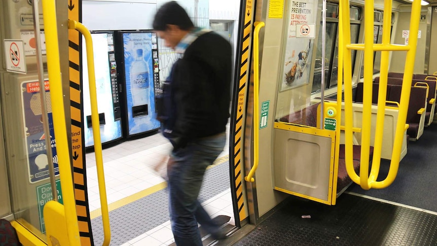 Blurred image of a man moving to exit a Brisbane train carriage