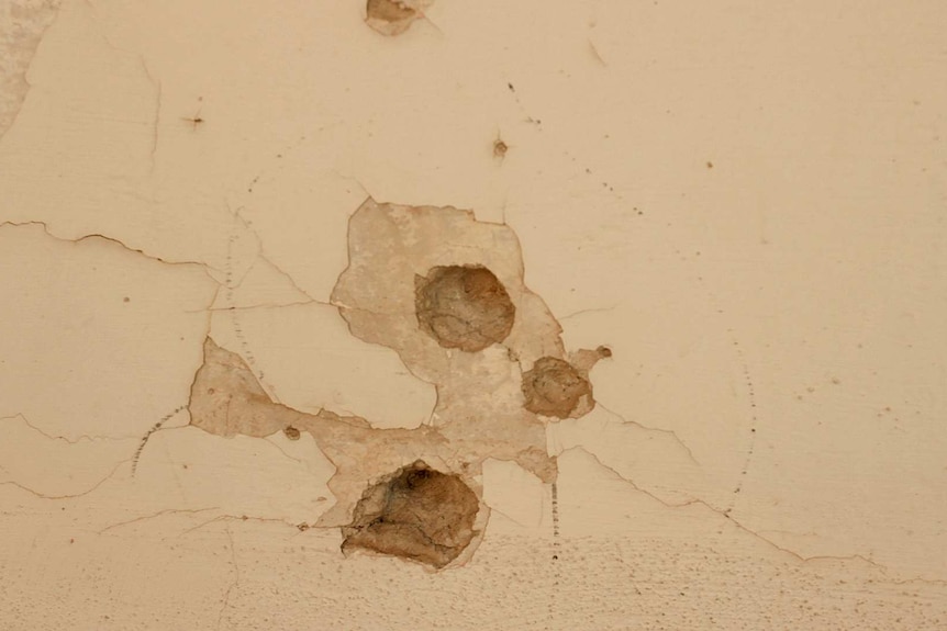 Bullet holes in a building wall.