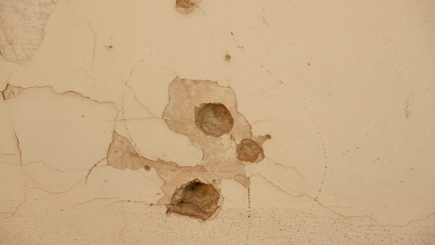 Bullet holes in a building wall.