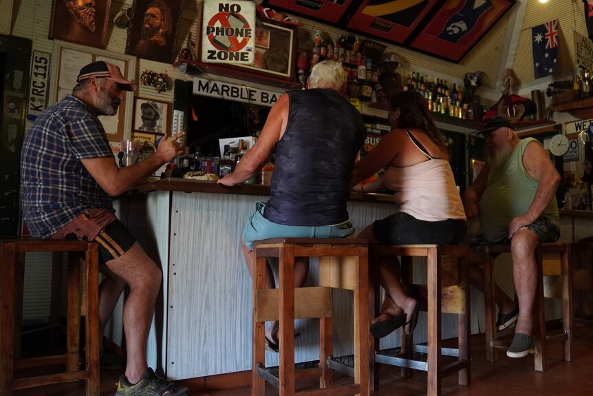 Four people sit at a bar with lots of signs adorning the walls.