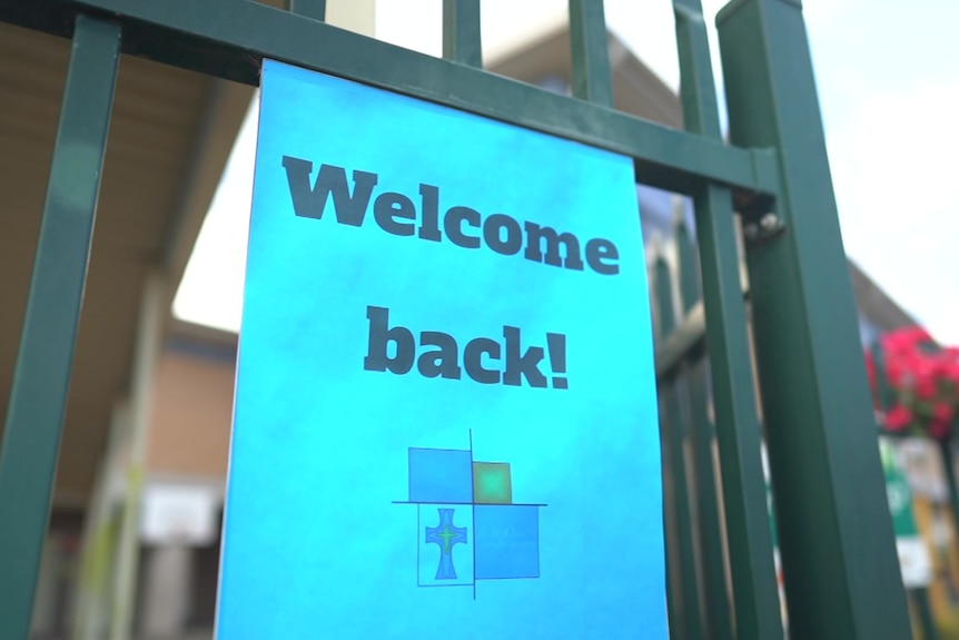 a sign that says welcome back hanging from a school gate