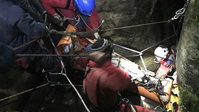 Rescuers remove a woman stuck in a cave crevasse.