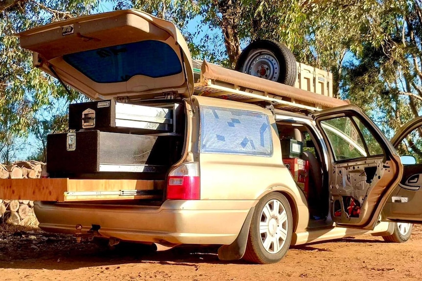 a parked stationwagon with all doors open and cargo sticking out the back